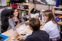 College counselor sitting at a desk talking to two students
