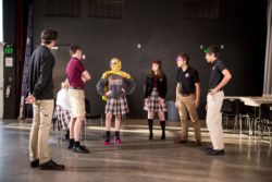 Student standing in a circle and doing a drama warm-up exercise.