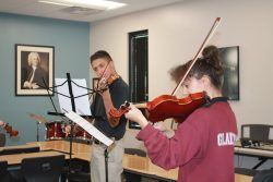 2 students each playing a violin.