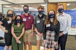 Three students and three parents stand in a line and pos for a picture while volunteering at the 2020 fundraising telethon event.