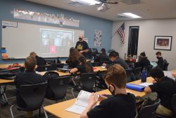 Teacher at the white board explaining a concept to a middle school class.