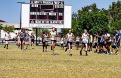 Cross country runners competing in an event by running the course that takes them across the soccer field.