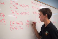 Student doing math problem at white board