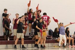 A group of student fans cheer excitedly at a sporting event in the gym.