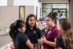 Four middle school students stand and talk.