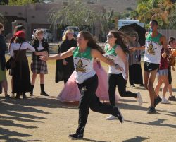 Three cross country runners get high fives from their class mates while running across the field.