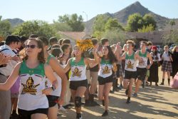 Student cross country runners run through a line of other students to receive high fives.